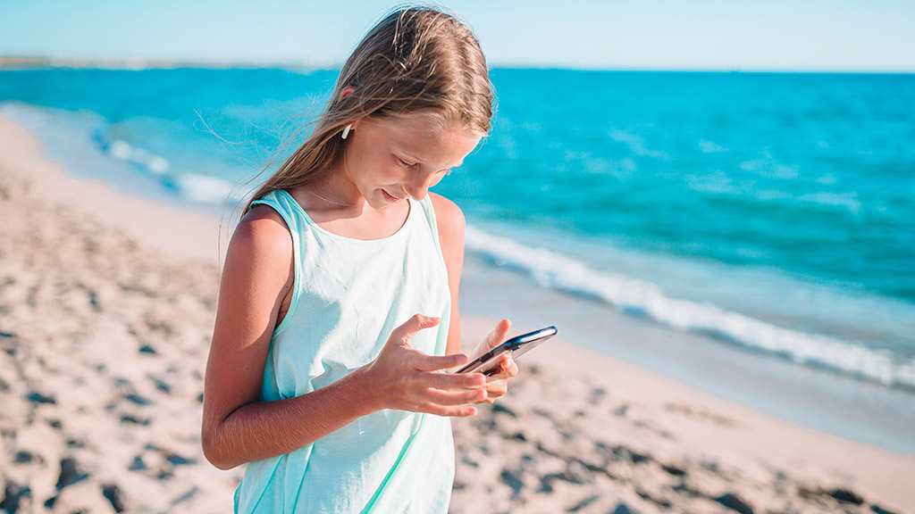 Bambina in vacanza con lo smartphone