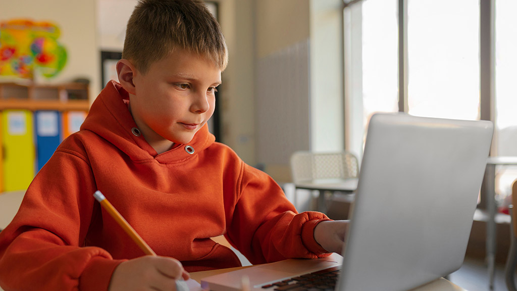 Bambino che fa i compiti scolatici al computer portatile